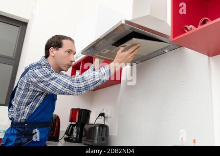 Close-up Of A Young Male Electrician Repairing Kitchen Extractor Filter Stock Photo