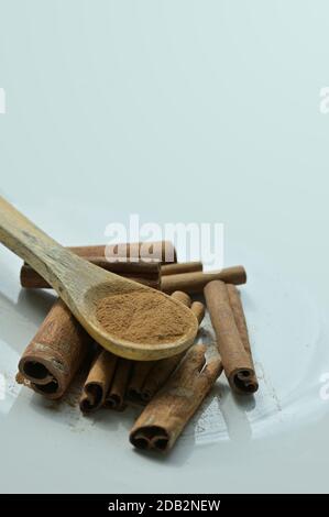 Close-up of Cinnamon bark powder and dried bark strips. Cinnamon is used as an aromatic condiment and flavoring additive in a wide variety of cuisines. Stock Photo