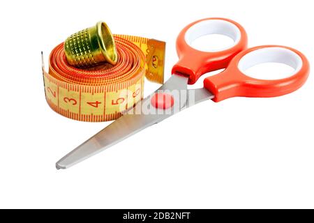 Sewing accessories and tools. Red sewing threads, black scissors, yellow  measuring tape and thimble on a white background. Stock Photo