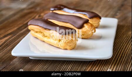 Eclairs with chocolate topping on serving plate Stock Photo