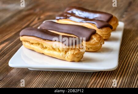 Eclairs with chocolate topping on serving plate Stock Photo