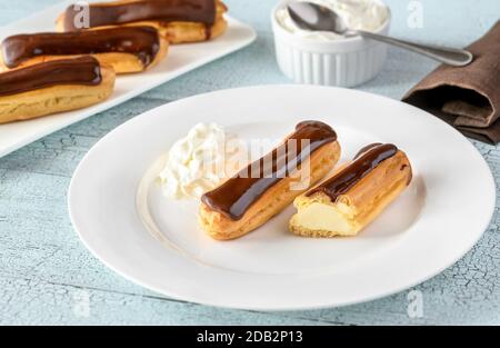 Eclairs with chocolate topping on serving plate Stock Photo