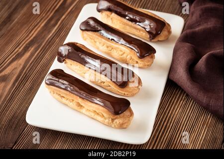 Eclairs with chocolate topping on serving plate Stock Photo