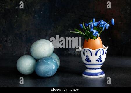 Easter eggs and snowdrops in an egg stand against a dark background Stock Photo