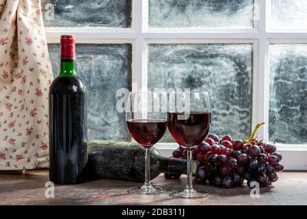 Composition with two wineglasses, grapes and bottles of red wine Stock Photo