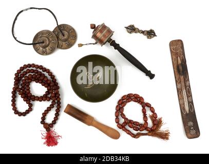 copper singing bowl, rosary, prayer drum, punitive, incense stand and wooden clapper. Set for prayers and meditations is isolated on a white backgroun Stock Photo