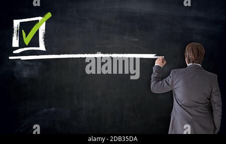 Businessman writing checkbox on blackboard concept. Stock Photo