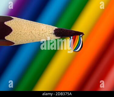 a drop of water on the tip of a pencil with a reflection of the colors of the rainbow Stock Photo