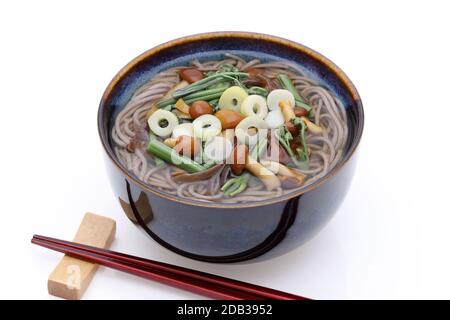 Japanese Sansai soba noodles in a ceramic bowl with chopsticks on white background Stock Photo