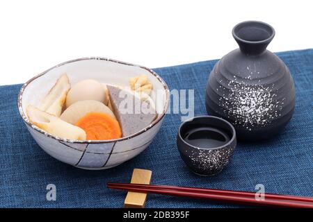 Japanese traditional sake cup and bottle with oden on table Stock Photo