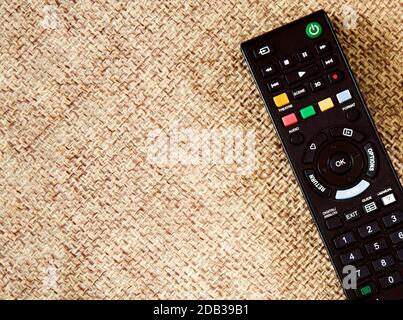 a black remote control of a television set on a patterned fabric surface Stock Photo