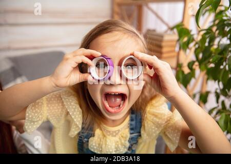 Laughting. Happy children, girl having fun in creativity of the house. Happy kid makes handmade toys for games or New Year celebration. Little caucasian model. Happy childhood, Christmas preparation. Stock Photo