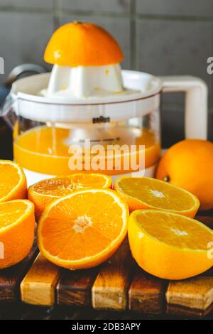 Old-fashioned Red and White Plastic Juicer with Halved Oranges for Juicing and a Glass of Freshly Squeezed Orange Juice - FOODPIX Stock Photo