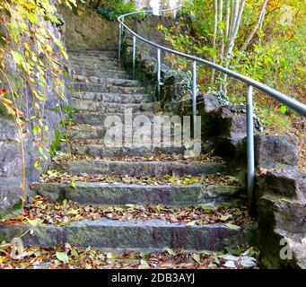 Outdoor staircase made of natural stones with a slight curve full of autumn leaves Stock Photo