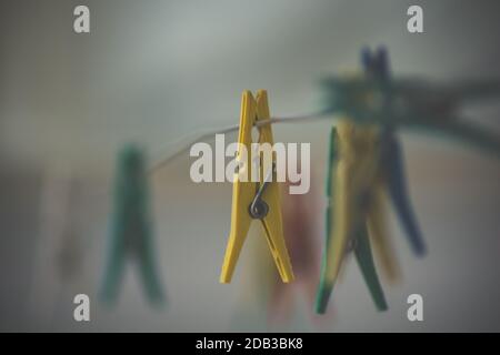 Colorful clothes pegs strung on a metal wire waiting for clothes to be hung. Stock Photo