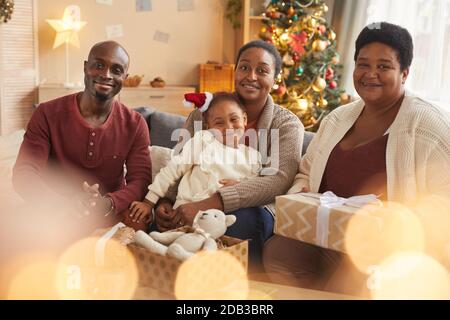 Magical portrait of happy African-American family looking at camera while enjoying Christmas at home Stock Photo