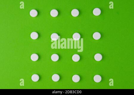 white pills laid out in the shape of a square on a green background. copy space for text. Stock Photo