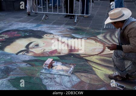 Street artist painting with chalk the portrait of the famous artist Frida Kahlo on the floor. Mexico, Mexico City. Stock Photo