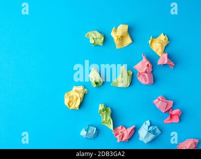 crumpled multi-colored paper stickers, top view, blue background Stock Photo