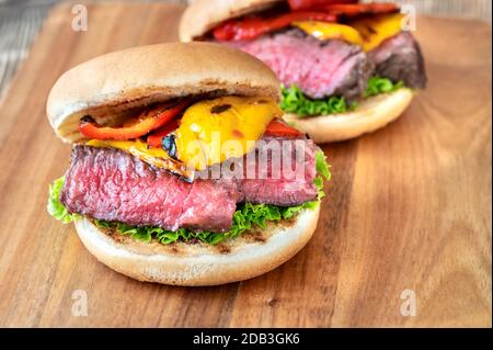 Sandwiches with grilled steak and bell peppers on wooden board Stock Photo