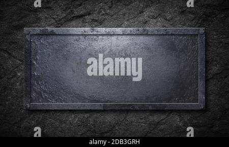 Old rusty metal sign with elongated shape and metal frame on rock wall Stock Photo