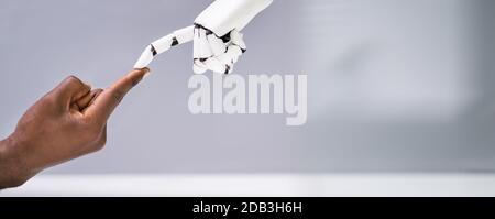 Robot Touching Human Finger Against Gray Background Stock Photo