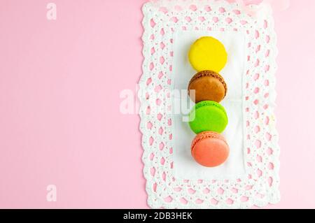 Several multicolored macaroons pastel colors on a white napkin on pink background. Stock Photo