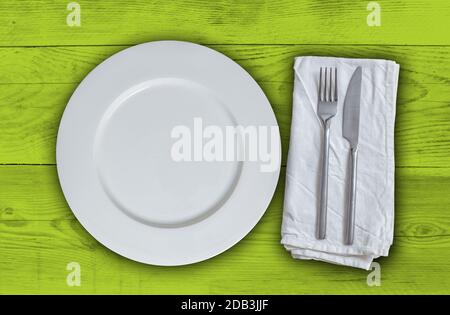 Empty plate with cutlery on light green vintage wood. Stock Photo