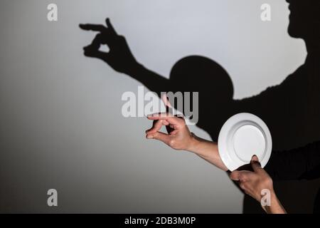 play shadow projected on a white screen. the person's hands and a plate form a snail Stock Photo