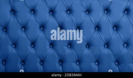 Close up background texture of dark blue capitone genuine leather, retro Chesterfield style soft tufted furniture upholstery with deep diamond pattern Stock Photo