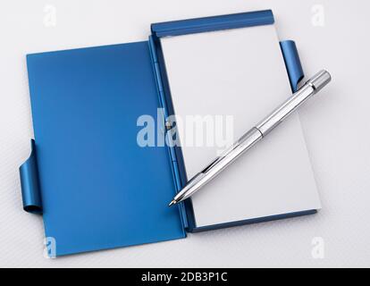 Open metallic notepad with white sheets and chrome pen Stock Photo