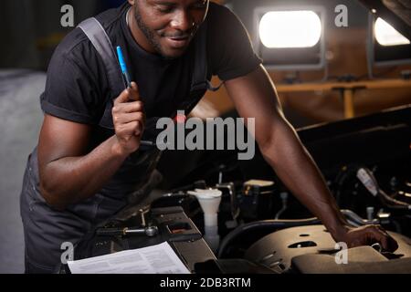 repairing in action. hardworking guy employee in uniform works in the automobile salon, confident auto mechanic is professional worker of service Stock Photo