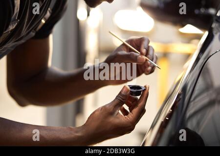 african man's hands use the detail brush to paint car or to clean and remove the dirt, car detailing and car wash painting concept. close-up, cropped male Stock Photo