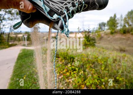 Hiker getting rid of sand from shoe, Empire, Michigan, USA Stock Photo