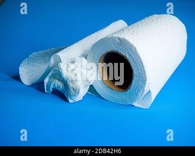 A closeup shot of a toilet paper roll and a scrunched up piece on a blue surface Stock Photo