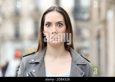 Front view portrait of a shocked young woman looking perplezed at camera on city street Stock Photo