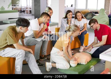 CPR class with male instructor speaking and demonstrating help, giving lessons of first aid. compression and resuscitation procedures. Cpr mannequin is used for an example Stock Photo