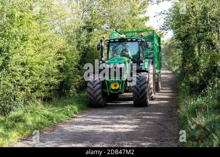 A large tractor and trailer on a track which is also a public footpath across a farm in the village of Irthington, Cumbria UK