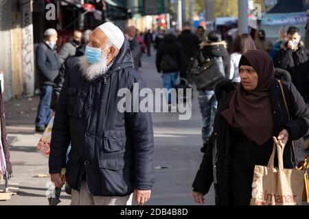 As Londoners from the mainly Bangladeshi Asian community await the second coronavirus national lockdown it's business as usual at Whitechapel Market with people out and about, some wearing face masks and some not, on what will be the few days of normality before a month-long total lockdown in the UK on 2nd November 2020 in London, United Kingdom. The three tier system in the UK has not worked sufficiently, to suppress the virus, and there have have been calls by politicians for a 'circuit breaker' complete lockdown to be announced to help the growing spread of the Covid-19. Stock Photo