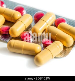 Red and yellow tablets and blisters scattered on a white background Stock Photo