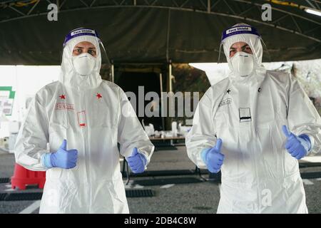 Two doctors with white disposable overalls and a protective covid mask do thumbs up. Ok sign, excellent sign. Turin, Italy - November 2020 Stock Photo