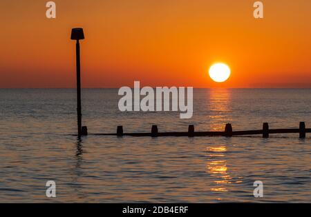 Landscape view of sunset over the sea or ocean in Autumn in the UK. Low setting sun. Stock Photo