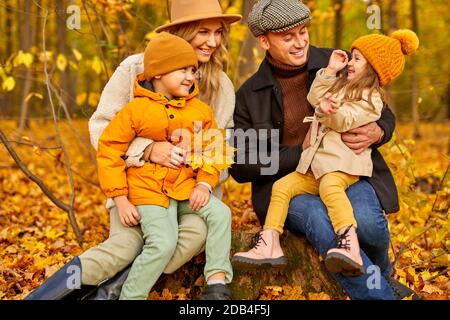 family have spare time in autumn park or forest, happily laughing smiling, wearing warm coats, sit surrounded by autumn leaves and trees. portrait Stock Photo