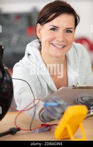 female electrician testing charge to spotlight Stock Photo