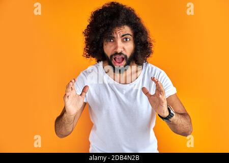 angry arabic man scream at camera isolated on orange background, handsome guy in casual wear show dislike Stock Photo
