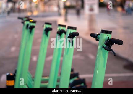 Green electric scooters for rent parked on the city. Stock Photo