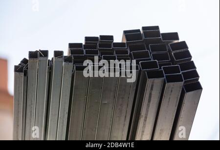 Many metal pipes stacked together on construction site during building works in city. Hollow structural section or square profile shape Stock Photo