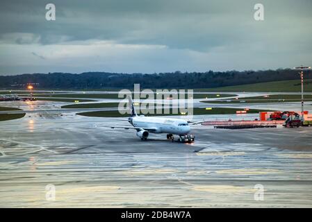 Lufthansa aircraft on taxiway in airport on cloudy evening after the rain, viewed from the terminal Stock Photo