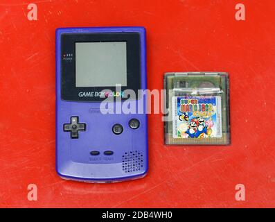 Vintage blue Game Boy by Nintendo with Super Mario Bros game lying alongside in a flat lay still life on a colorful red background in an entertainment Stock Photo