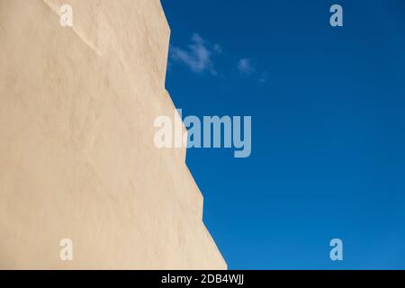 Building wall beige yellow color with zigzag edge located against bright blue sky background, copy space, template Stock Photo